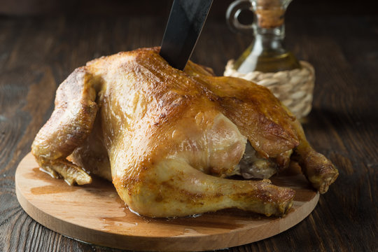 Whole roasted chicken on cutting board with black khife