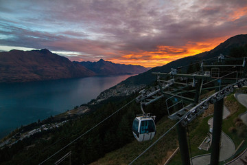 Colourful sunset view of the lake Wakatipu, resort town and mountains with gondola skyline, Southern Alps, Queenstown New Zealand, Cecil peak, Walter peak and Queenstown hill