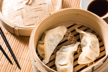 Dumplings or gyoza served in traditional steamer on bamboo mat