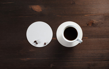 Cup of coffee and beer coaster on wood table background. Flat lay.