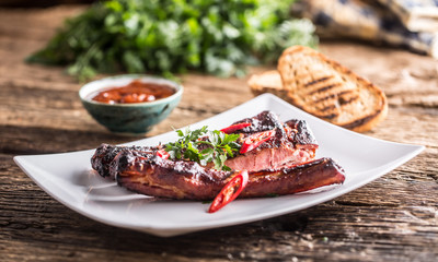 Tasty barbecue grilled pork ribs with chili pepers and parsley herbs.