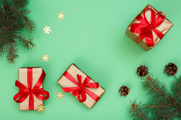 Gift boxes, fir tree branches with decorative snowflakes on green background