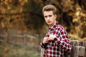 Naklejka na ściany i meble Handsome young guy in nature on an autumn day