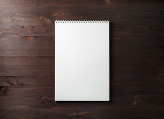 Blank spiral sketchbook on wood table background. Responsive design template. Space for text. Flat lay.