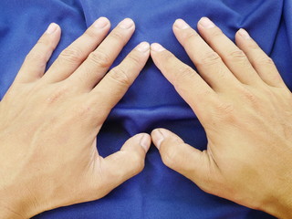 Fototapeta premium women hand on blue cloth background,texture of silk fabric