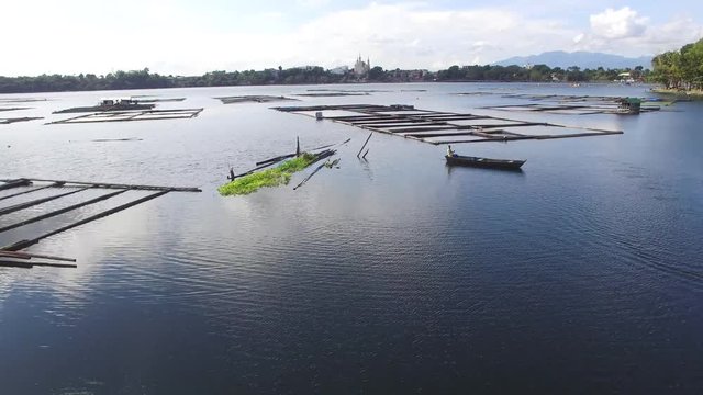 Sampaloc Lake, San Pablo City, Laguna, Philippines - November 21, 2017: boatman paddle tiny wooden fishing boat on mountain lake.  Drone aerial shot