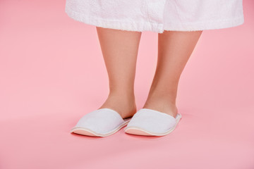 cropped shot of young overweight woman in white slippers and bathrobe standing on pink