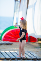 Obraz premium Summer lifestyle portrait of pretty girl swimming posing on the back on the inflatable watermelon in the ocean, wearing stylish bikini swim wear in black and hat. Relaxing and enjoying life.