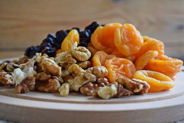 Useful dried fruits and walnuts on wooden background.