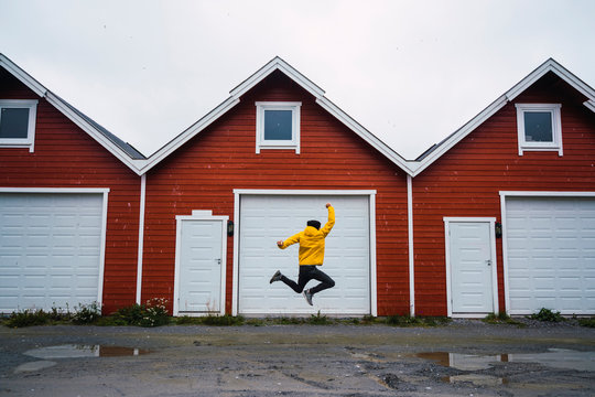 Norway, man jumping in front of row of huts