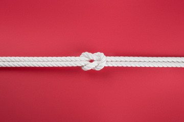 White ship ropes connected by reef knot on red