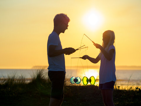 France, Bretagne, Sainte-Anne-la-Palud, La Plage de Treguer, brother and sister juggling with diabolo at sunset
