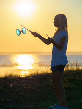 France, Bretagne, Sainte-Anne-la-Palud, La Plage de Treguer, girl juggling with diabolo at sunset