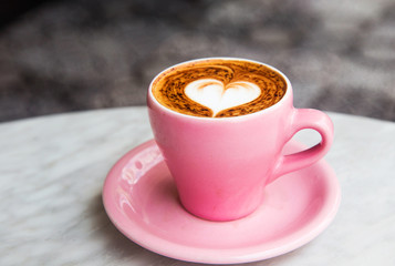 Cappuccino cup with heart latte art on marble table background.