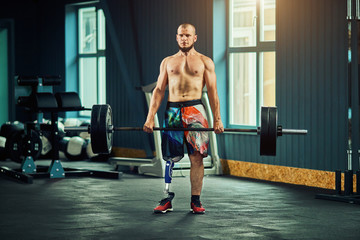 Naklejka na ściany i meble Sportsman with prosthesis working out in gym