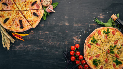 Background of Italian food. Assortment of pizza. On a black wooden background. Free space for text. Top view.
