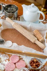 Rolling pin with a pattern on a wooden decorated table covered with baked flour. Rolled dough with a pattern and cookie of various shapes. Biscuit cooking background, top view