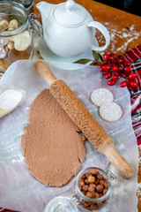 Rolling pin with a pattern on a wooden decorated table covered with baked flour. Rolled dough with a pattern and cookie of various shapes. Biscuit cooking background, close-up