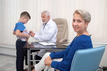 Fototapeta premium Mother smiling, waiting on doctor examining her son.