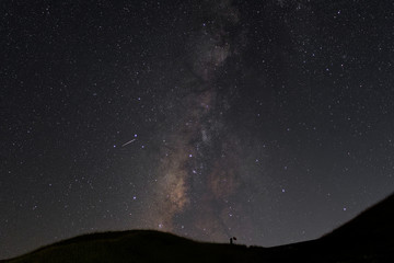 A view of a Meteor and the Milky Way with mountain silhouette in the foreground. Night sky nature...