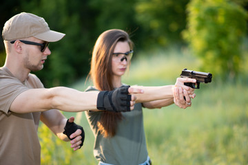 the instructor teaches the girl to shoot a pistol at the range