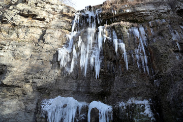 Fototapeta na wymiar Beautiful frozen waterfall in Kamianets-Podilskyi city, western Ukraine