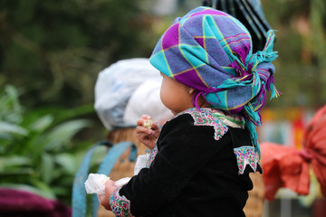 Hmong girl dressed in colorful hand-woven cloth in hand holding food at Lao Cai, Sapa Vietnam 21...