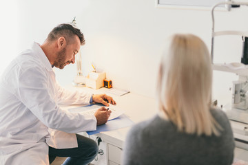 Doctor filling medical questionnaire with a patient.