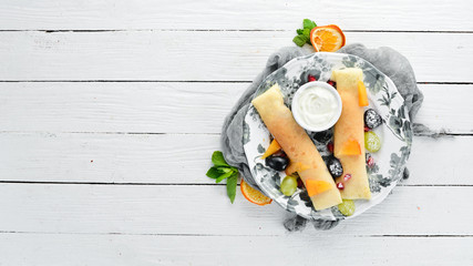 Pancakes with fruit and sour cream. Dessert. On a wooden background. Top view. Free space for your text.