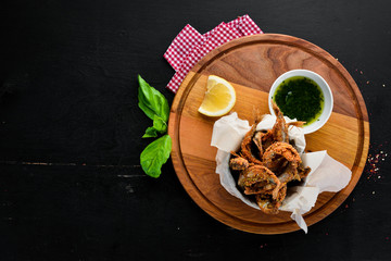 Fine fish baked in oil with sauce. On a wooden background. Top view. Free space for your text.