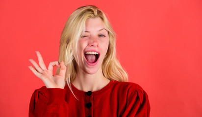 Things gonna be alright. Girl wink happy face while show ok gesture over red background. Woman...