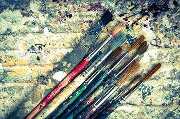 old paint brushes on grungy dried paint background, grungy vintage style cross processed effect