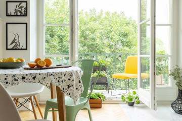 Copper mint chair placed by the table with fresh fruits and lastrico tablecloth in real photo of white room interior with balcony with plants and lights - obrazy, fototapety, plakaty