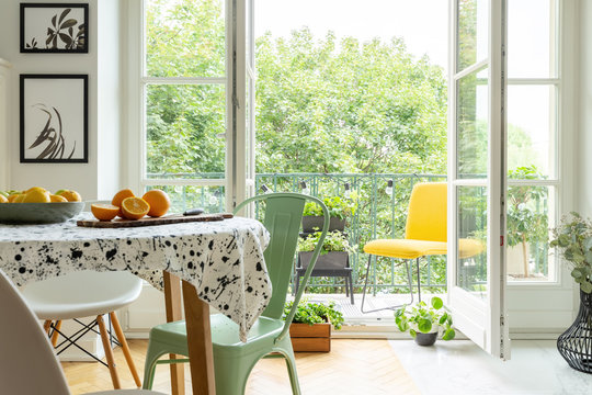 Copper mint chair placed by the table with fresh fruits and lastrico tablecloth in real photo of white room interior with balcony with plants and lights