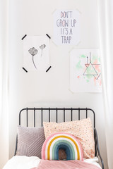 Closeup of drawings on the white wall of kids bedroom with colorful bedding, real photo
