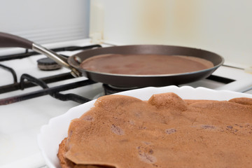  Cooking chocolate pancakes in the kitchen and ready-made chocolate pancakes in the foreground