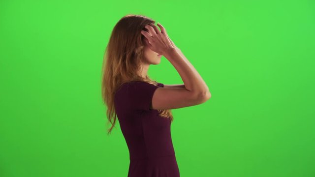 Young woman walking in a medium sideways shot over a green screen, felling ill and upset, casual look.