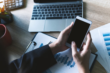 Closeup view of business women working using smart mobile phone for checking text message with finance graph at table. business technology concept.