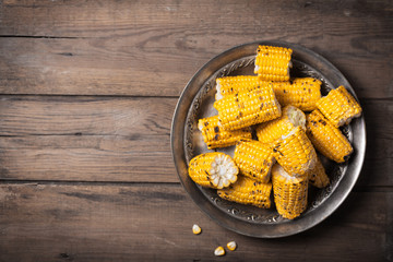Grilled corn cobs on the metallic rustic plate. Top view with free space