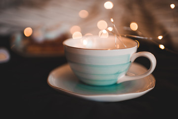 Cute cup with lights at background closeup. Christmas holidays.