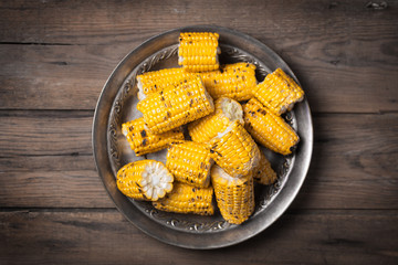 Cutted corn cobs on the brown rustic plate at the center of image