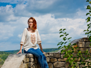 Naklejka na ściany i meble Beautiful young girl with red hair posing against nature background.