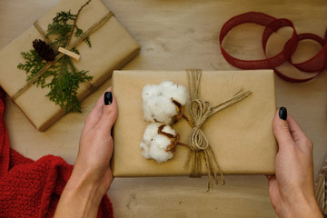 Woman holding Classy Christmas gift box present on brown paper. Christmas presents with handmade decoration. Top view