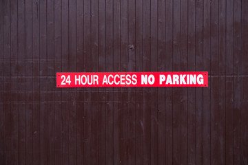 24 hour access no parking sign red and white on wooden access door