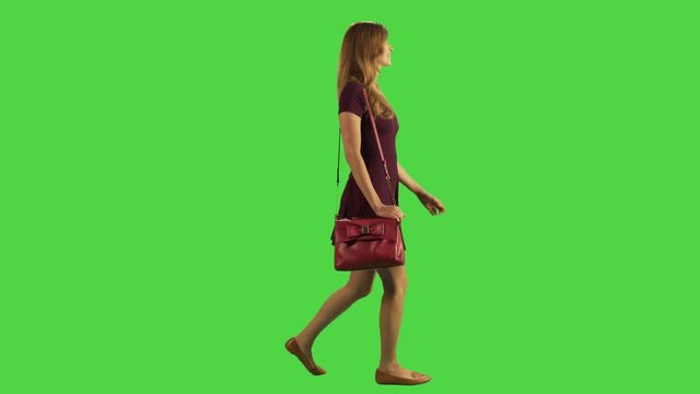 A young woman walking sideways feeling ill and upset in a full body shot over a green screen.