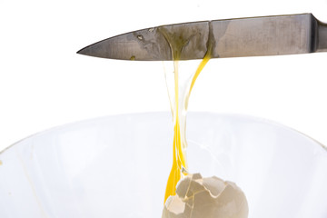 The falling egg breaks on the blade of a knife
