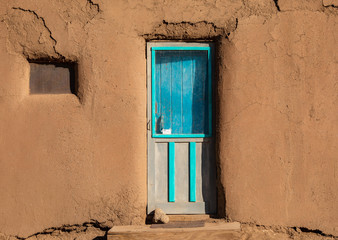 Turquoise door in brown clay wall