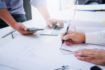 Close up of civil male engineer asian working on blueprint architectural project at construction site at desk in office.