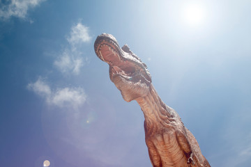 Obraz premium Statue Dinosaur opens its mouth under the blue sky.