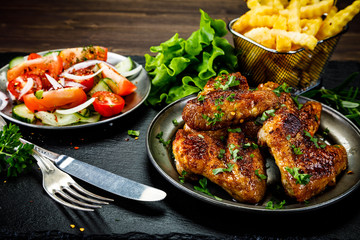 Roast chicken wings with french fries and vegetable salad 